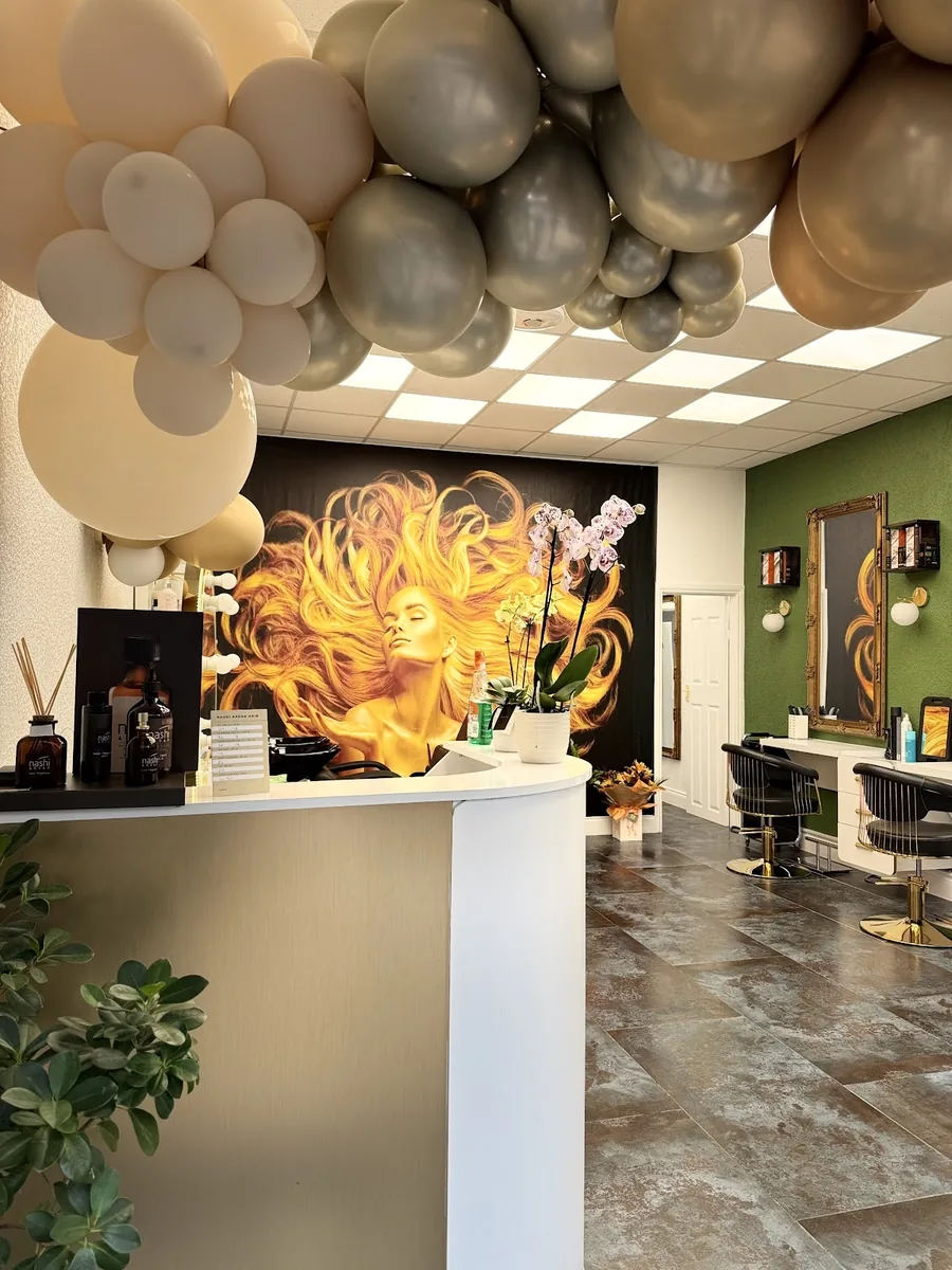 The salon interior looking toward the reception desk, with the flame-haired mural on the green wall