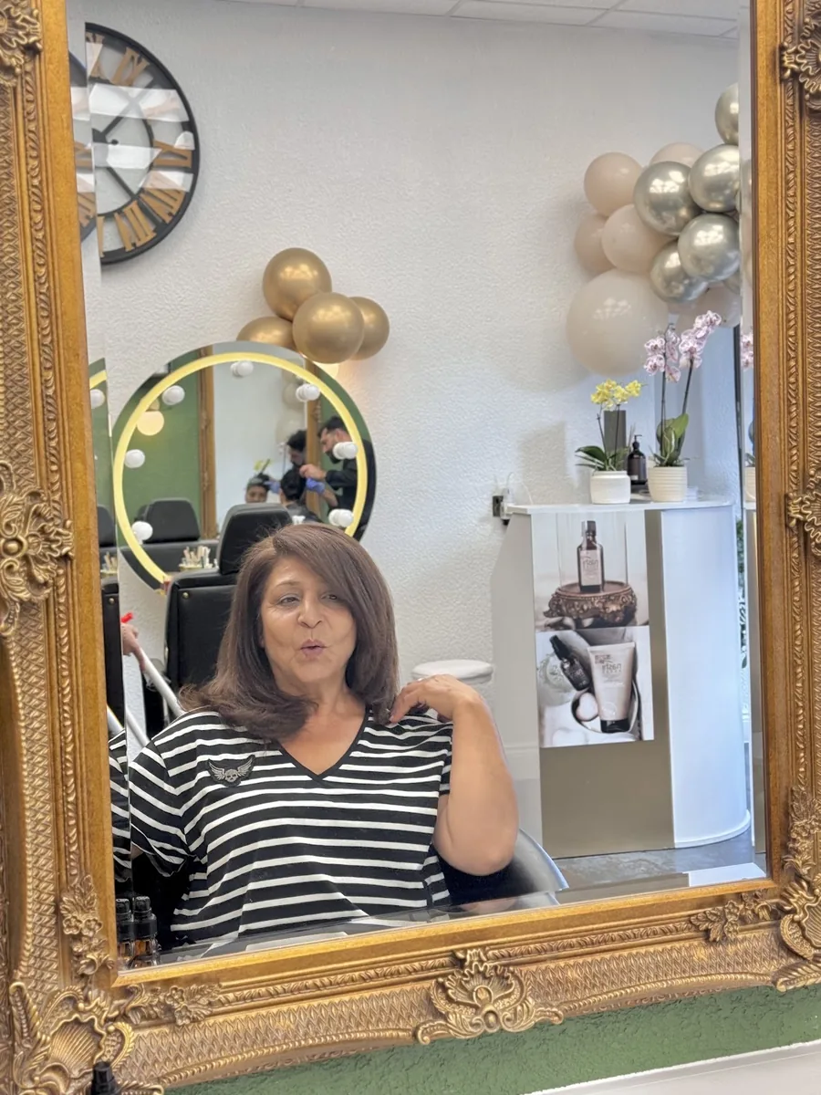 A client in front of the large gold-framed mirror with a freshly finished blow-dry